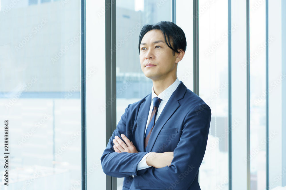 Fototapeta premium 窓際に立つミドルエイジの日本人男性のポートレート 撮影協力：学校法人電波学園 東京電子専門学校