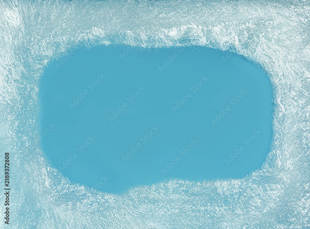 Obraz premium Blue icy frost texture background with dense frozen winter patterns on glass window with an empty blue space in the middle for seasonal backgrounds.
