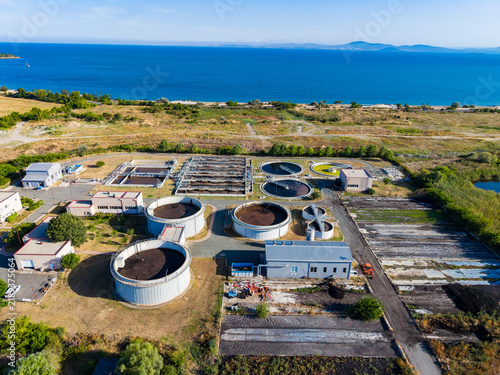 Konstfotografi Water treatment facility near the coastline with several round tanks and buildin