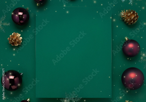 Minimalist Christmas frame with red baubles on green background with copy space