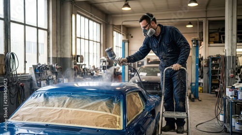 Professional Auto Mechanic Spray Painting a Classic Car in a Workshop.
