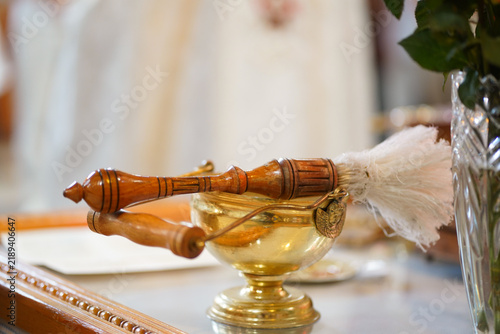 Obraz na płótnie Wooden aspergillum rests above a vessel of holy water, prepared for use during a church service and baptismal ritual