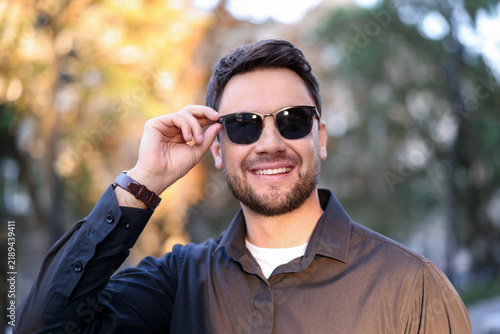 Handsome man wearing stylish sunglasses on city street