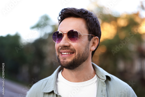 Handsome man wearing stylish sunglasses on city street