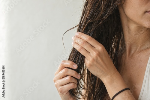 Woman works the oil into her ends the moment a strand slips free of her palm, hair care routine with copy space