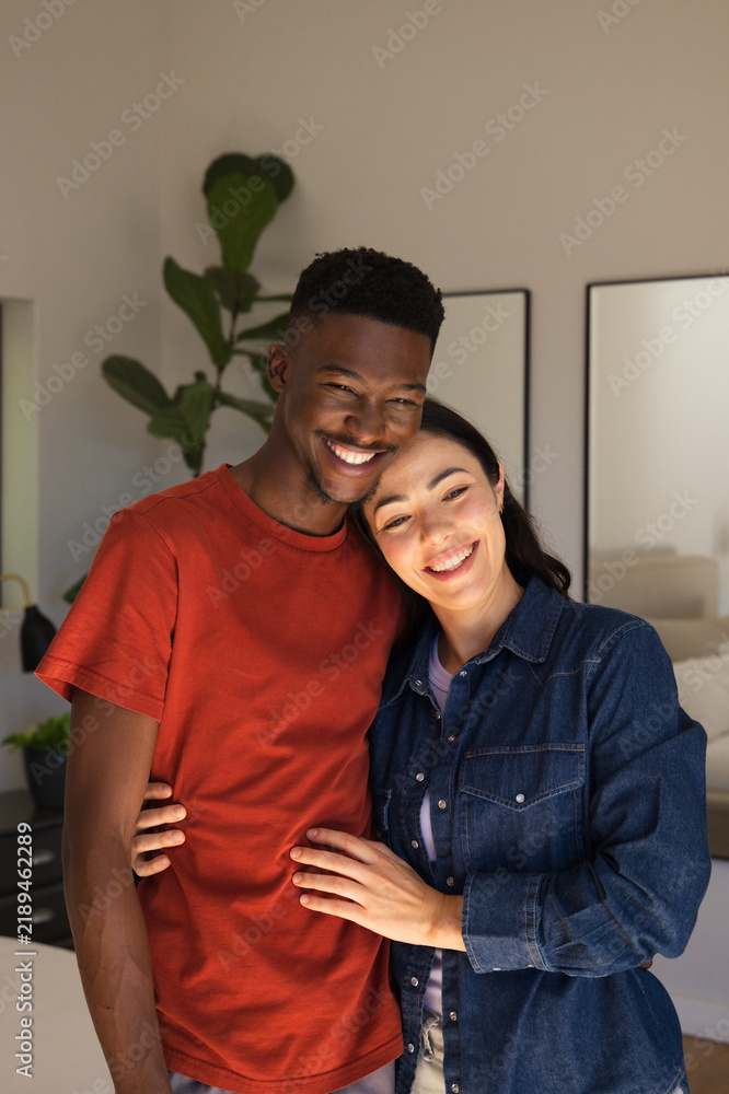 Fototapeta premium Diverse couple standing in bedroom, woman leaning on man's shoulder, wearing denim, with fig plant