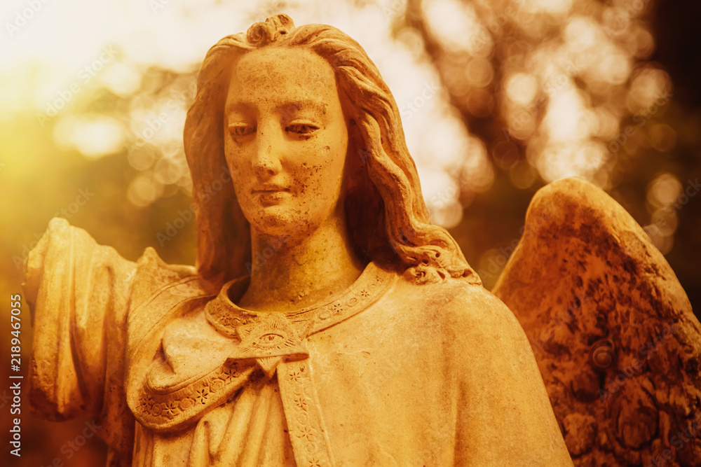 Fototapeta premium Guardian angel statue illuminated by warm golden sunlight, symbol of divine protection, faith, hope and spiritual guidance.