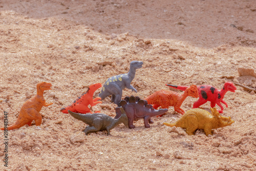 A variety of toy plastic dinosaurs figurines arranged on sand