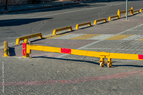 Fotografie Yellow parking bollard with red reflective bands on paved surface