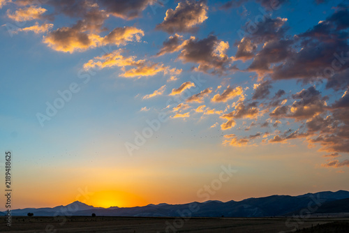 Golden hour sunset paints the sky with vibrant colors over rolling hills