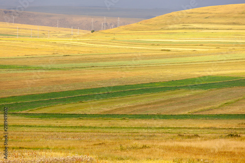 Vast rolling hills under a dramatic sky with agricultural fields below