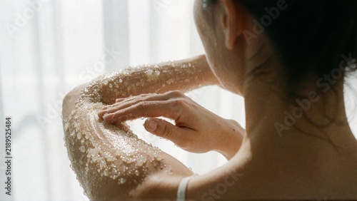 Woman Applying Body Lotion in Window Light.
