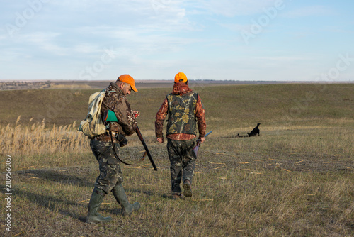 Mature man hunter with gun while walking on field.