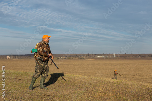 Mature man hunter with gun while walking on field.