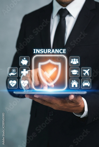 Businessman holding digital tablet with glowing insurance shield and icon menu interface overlay
