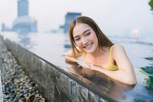 Konstfotografi Radiant young woman relaxing in rooftop infinity pool at twilight, enjoying luxury travel, serene city skyline escape, tranquil wellness, refreshing leisure vacation, and pure blissful hospitality
