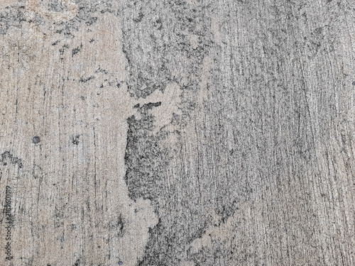 Gray concrete road surface shows rough, abstract texture