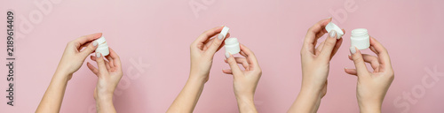 Hands opening white cream jar on pink background