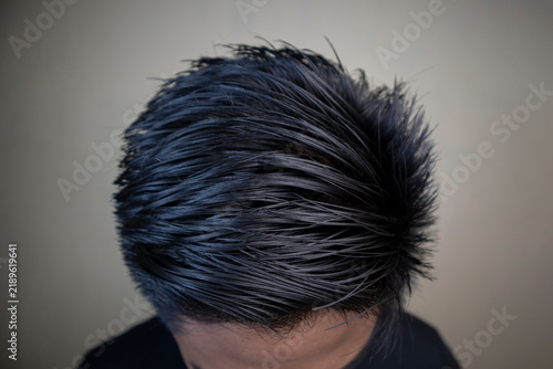 overhead shot of textured black short hair styling on a person against a neutral background.