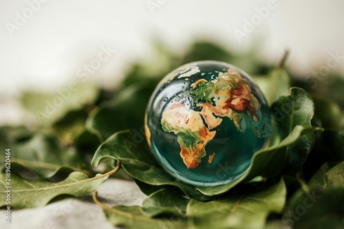Small globe sphere placed on dried brown fallen leaves symbolizing world ecology with environment conservation sustainability protection earthday ecosystem biosphere environmental earthcare