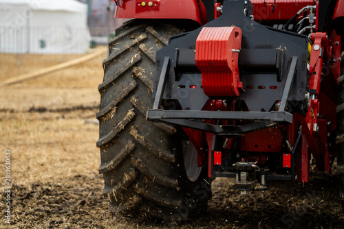Cuadro en lienzo Rear view of a heavy red farm tractor with large off-road tire, hitch system, and counterweight in a field