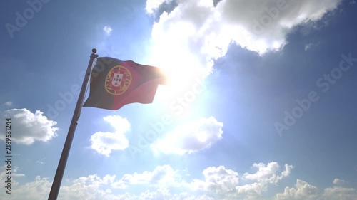 Portugal Flag waving on a Flagpole from a Moving Angle in front of a blue sky with clouds	