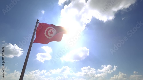 Tunisia Flag waving on a Flagpole from a Moving Angle in front of a blue sky with clouds	