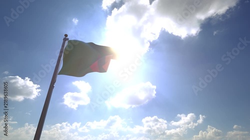 Zambia Flag waving on a Flagpole from a Moving Angle in front of a blue sky with clouds	