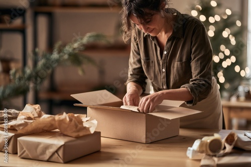 Small business owner packing Christmas orders in home studio