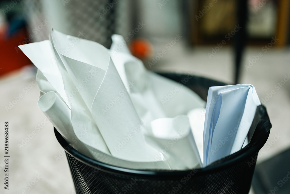 Obraz premium Paper wastebasket filled with crumpled white paper and empty disposable cup, highlighting office clutter and recycling needs indoors