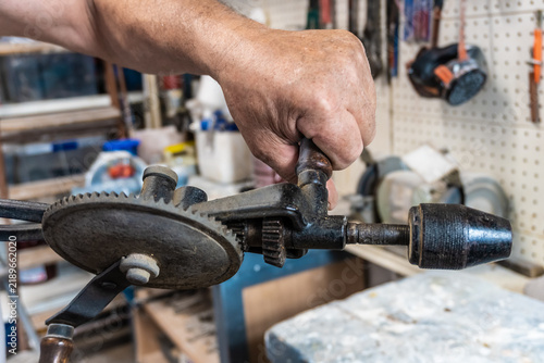 Obraz na płótnie Worker using a vintage hand drill in a workshop