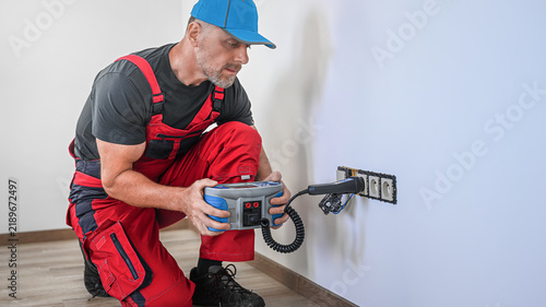 фотографія A electrician using multifunction tester for revision of electrical circuits