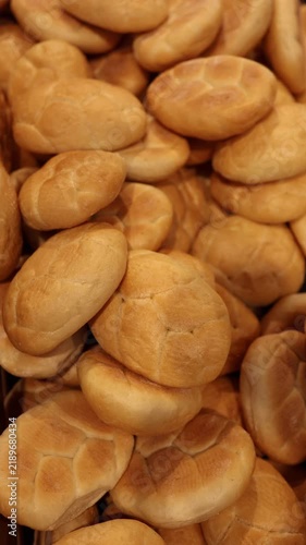 Vertical screen fresh bread rolls displayed in bakery section with golden crust and traditional round shape showing everyday wheat bread ready for sale in a grocery store