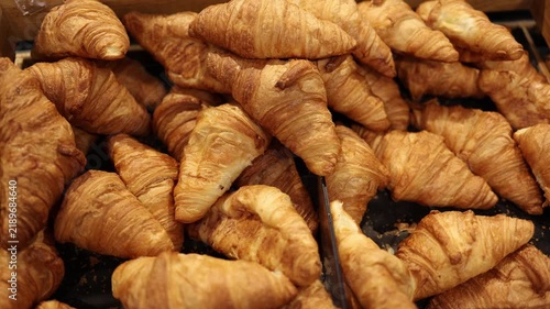 Fresh golden croissants fill supermarket bakery display with flaky layered pastry and buttery crust offering classic breakfast food and freshly baked treats for customers
