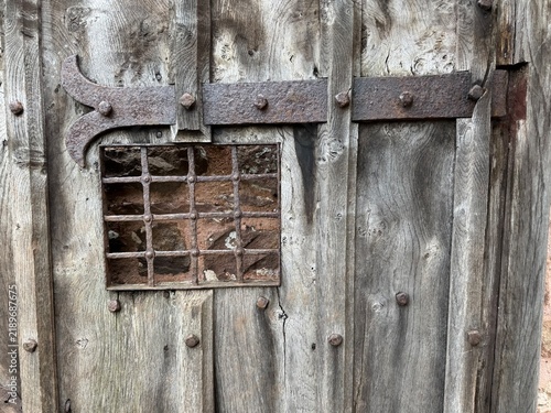 A beautiful ancient wooden door with an iron grid and hinge. England, UK.