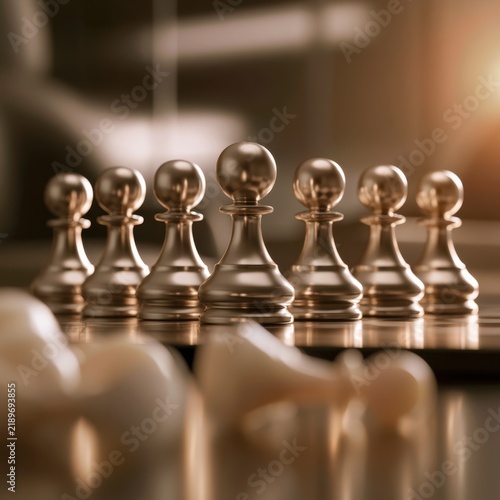 Metallic chess pawns standing firm in focus with fallen white chess pieces blurred in the foreground symbolizing strategy and competition in a warm setting