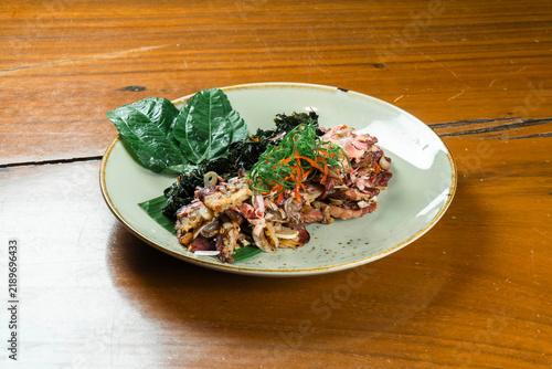 Exotic Seafood Delight: A gourmet seafood dish, artfully presented with fresh greens and seaweed, rests on a rustic wooden table, offering a taste of oceanic luxury.