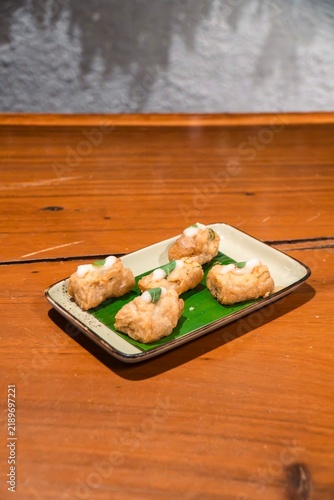 Crispy Delight: A rectangular plate showcases six golden-brown fried delights, each meticulously garnished with a sprinkle of white and a fresh green leaf.
