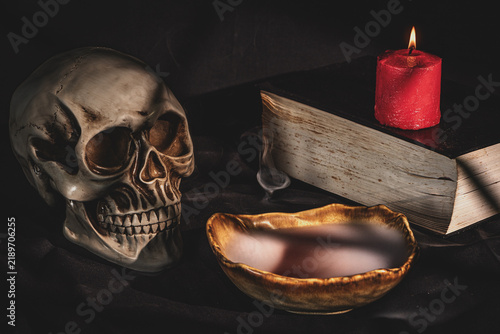 Cuadro en lienzo Human skull with burning candle, ancient book and mysterious red potion in smoki