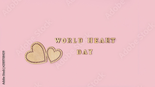 Foto World Heart Day message with handcrafted wooden hearts and lettering on a soft p