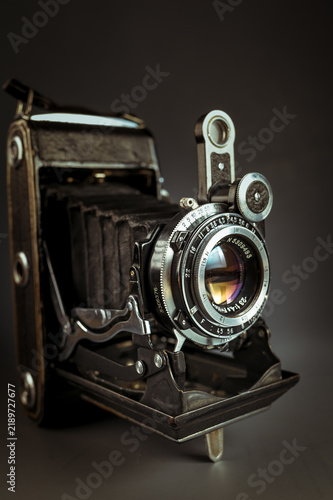 Bild auf Leinwand Vintage folding camera with leather bellows on a dark low key background