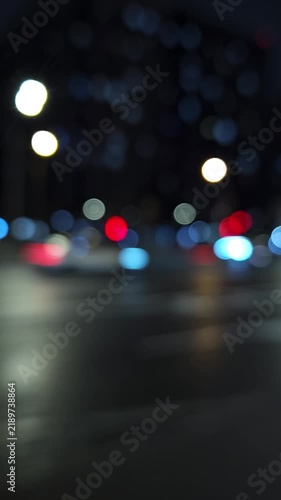 Atmospheric defocused night traffic with glowing city lights and reflections on wet pavement, creating a cinematic urban background for transportation, mobility, nightlife and modern city concepts