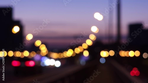 Defocused urban traffic with glowing road lights during evening commute, creating an atmospheric city background for transportation, mobility, infrastructure and modern metropolitan concepts