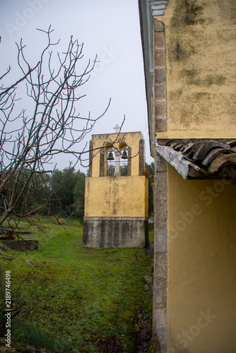 Фотография Yellow campanile bell tower with two bronze bells standing separate from the chu
