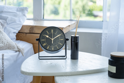 Black Table Clock and Reed Diffuser on White Table in Bedroom