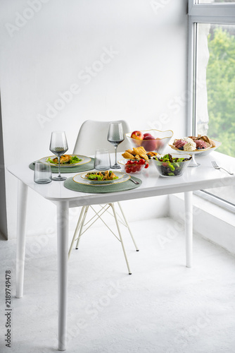 A dining table set with food and drinks in a bright room