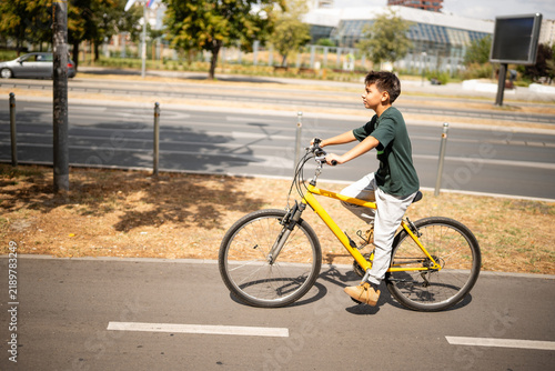 Canvastavla Boy riding yellow bicycle on city bike lane