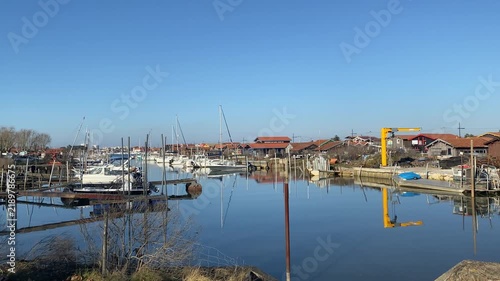 View of Arcachon, France, with small boats along the waterfront and the town's buildings in the background. The coastal scene reflects the maritime character and relaxed atmosphere. 