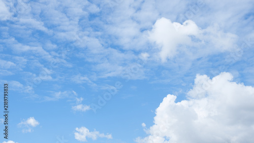 Nature and sky photography featuring a bright blue sky filled with white fluffy cumulus and cirrocumulus clouds, representing weather, atmosphere, serenity, freedom.