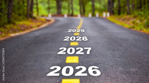 Years 2026 to 2029 written on an asphalt road leading into a blurred forest background during the daytime